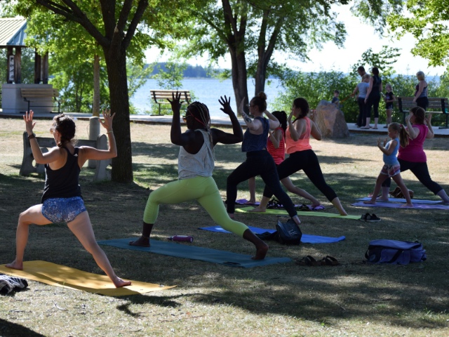 A group of people doing yoga in a waterfront park.