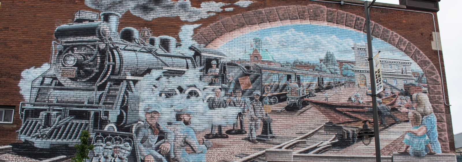 The Pembroke Heritage Murals mural "Grand Trunk Union Station" showing a train station with people working and watching trains.