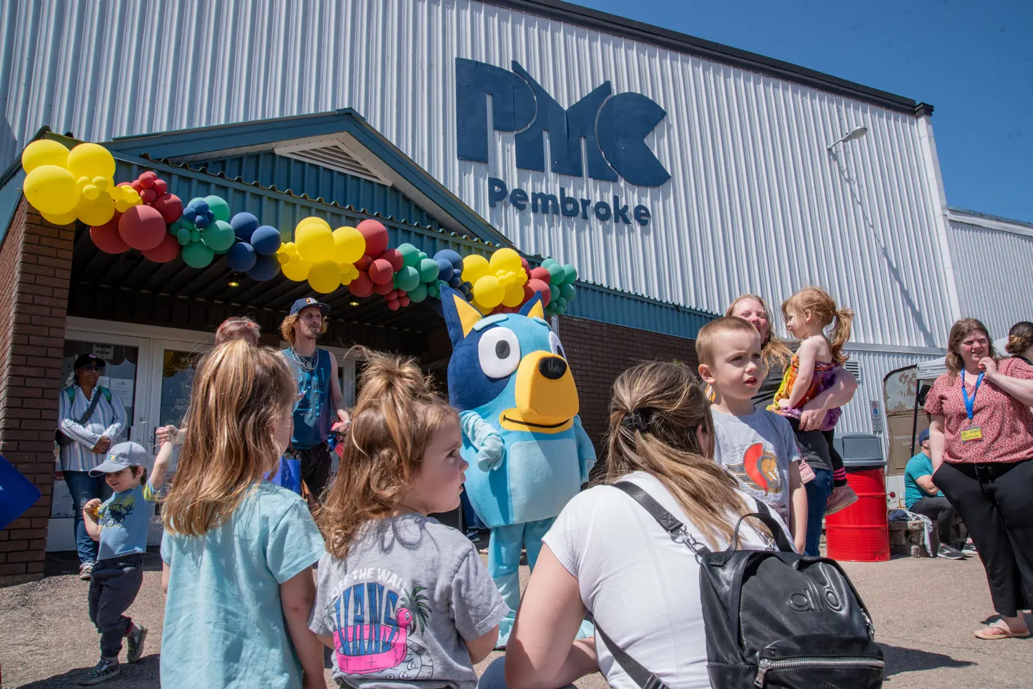 A group of people say hello to a mascot.