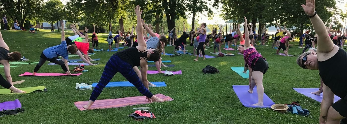 People doing yoga outside in a park.