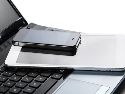 A cellphone, tablet, and laptop in a pile.