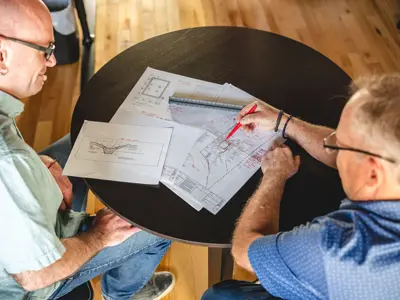 Two men looking at papers on a table.
