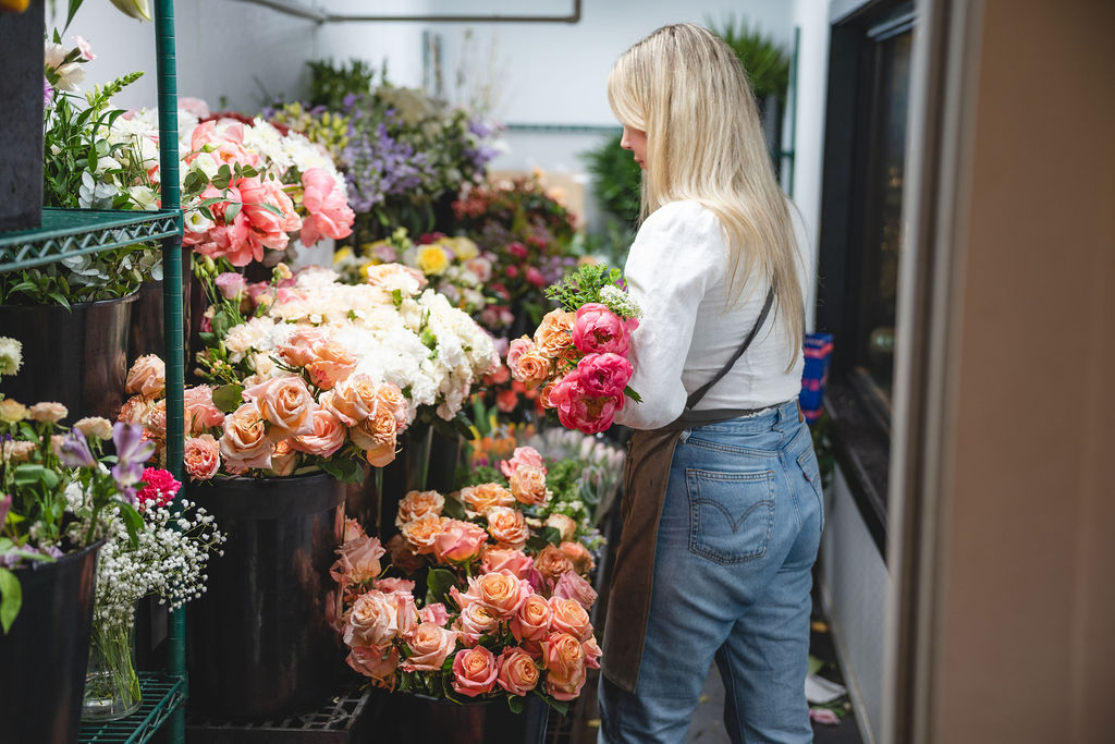A woman picking flowers from a cooler.